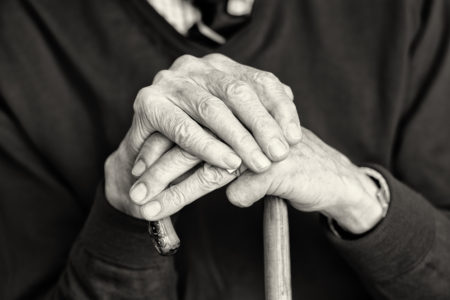 old man's hands leaning on can