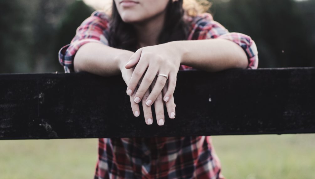 woman with arms crossed leaning on fence rail