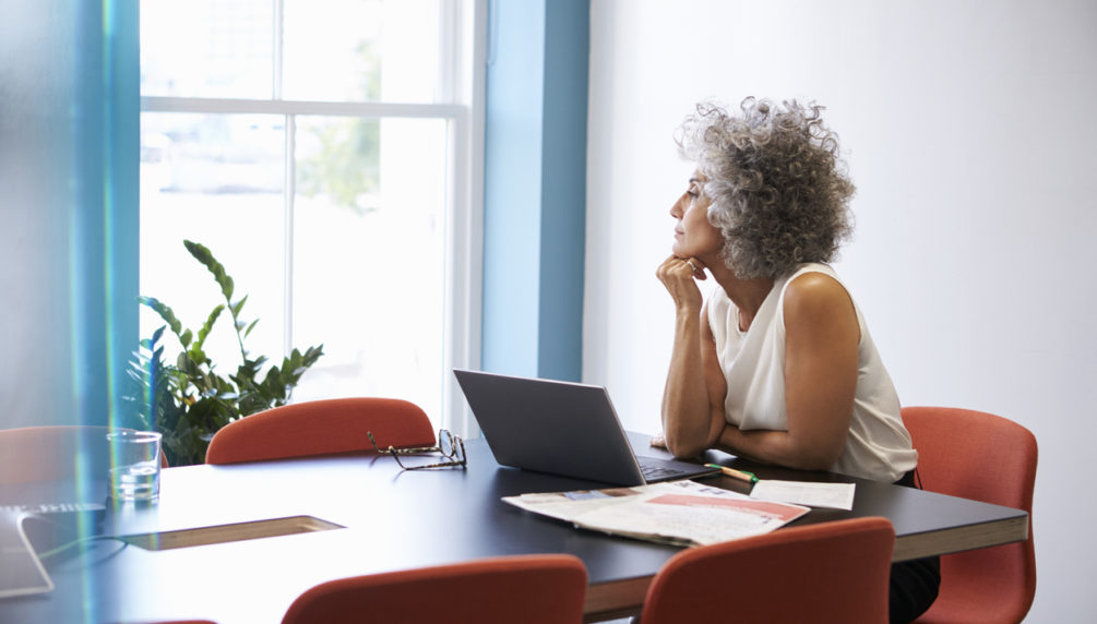 Middle aged woman looking out of the window in the boardroom