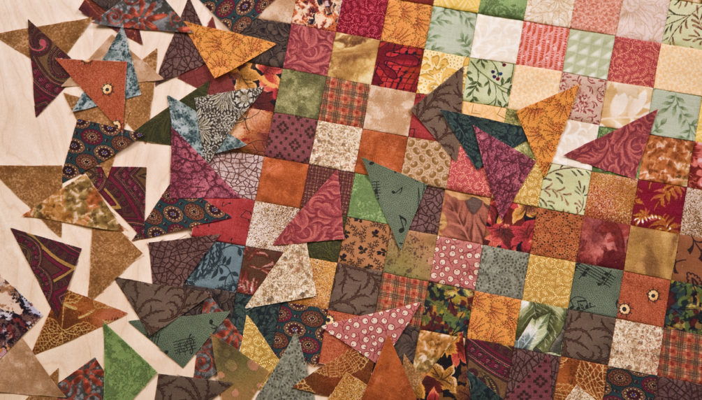 High resolution close up of tiny 1 inch square fabrics pieced together into a quilt.